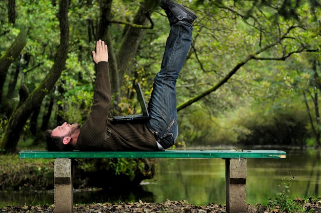 one young businessman working on laptop outdoor with green nature in background