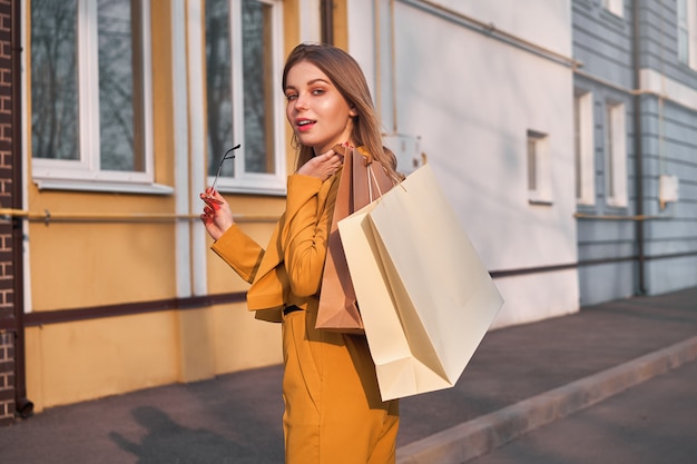 Una giovane ragazza europea caucasica shopaholic che cammina lungo la strada con acquisti in pacchetti.