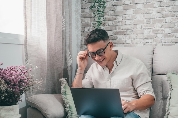 One young happy man surfing the net using his laptop at home\
sitting on the sofa enjoying free time and relaxing alone\
entrepreneur boy working and building his futurexa