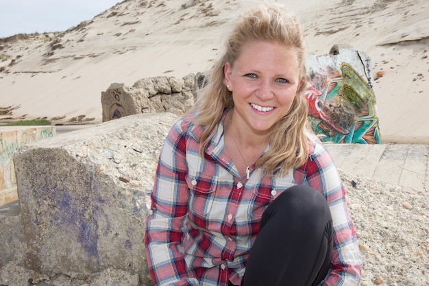 One young woman with blond hair sitting on the beach