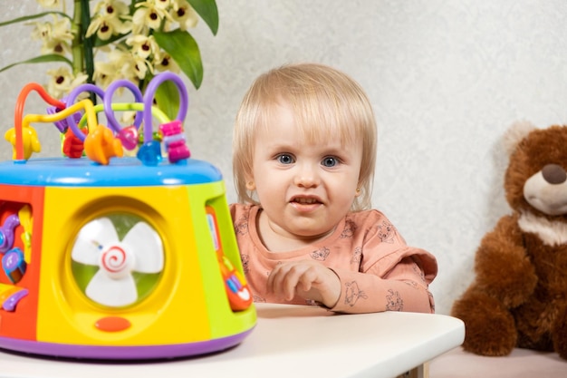 A oneandahalfyearold girl plays with a musical glowing toy presses buttons