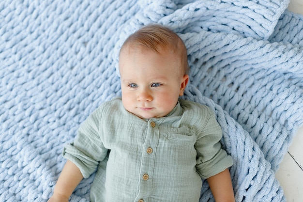 シャツを着た1歳の青い赤ちゃんが毛布の上に横たわっている高品質の写真