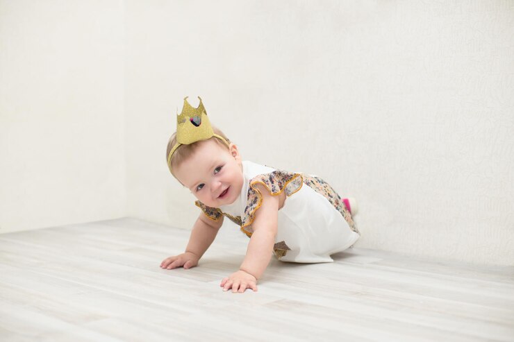 A oneyearold girl with a crown The little princess crawls on the floor