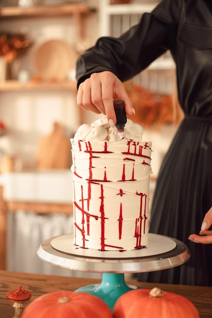 Photo onfectioner woman decorates a cake with blood for halloween cake idea