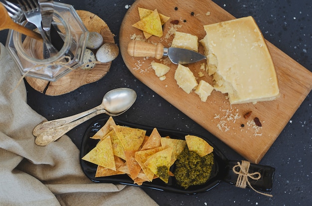 Ongebruikelijke dienende plaat gemaakt van fles met zelfgemaakte chips en Italiaanse pestosaus en parmezaanse kaas