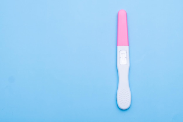 Foto ongebruikte roze en witte zwangerschapstest op de blauwe achtergrond met kopieerruimte
