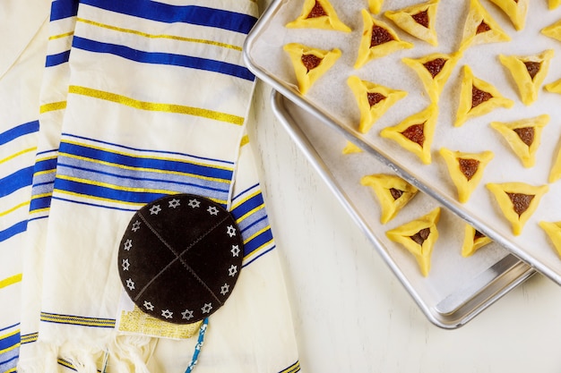 Ongekookt hamantaschen koekjes op bakplaat met kippa en tallit