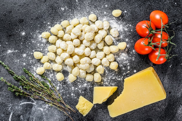 Ongekookt zelfgemaakte gnocchi op zwarte snijplank. Zwarte achtergrond. Bovenaanzicht