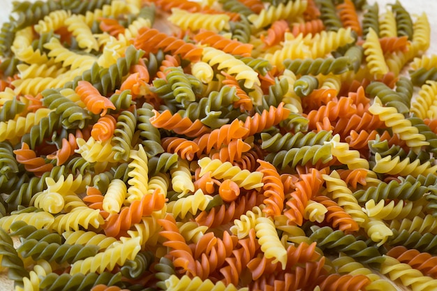 Ongekookte driekleurige Italiaanse pasta Gedroogde Italiaanse pasta op een houten tafel Gekleurde natuurlijke pasta