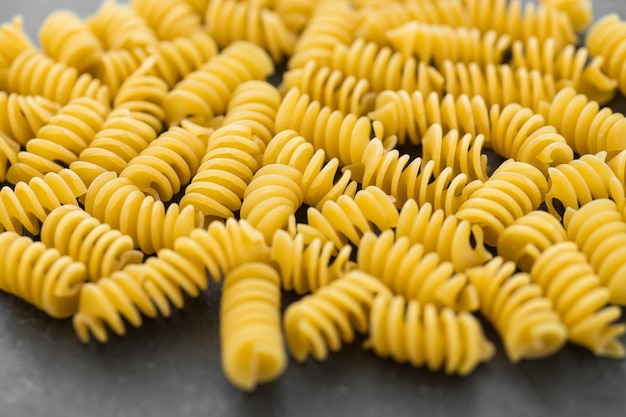 Ongekookte eliche pasta geïsoleerd op een donkere achtergrond met uitknippad