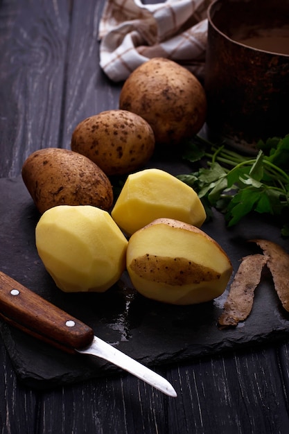 Ongekookte gepelde aardappels op donkere achtergrond