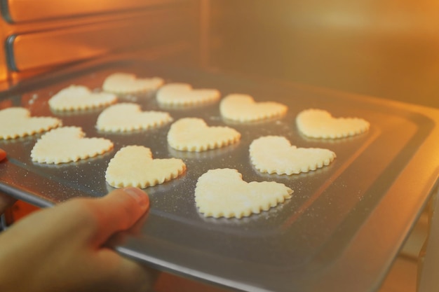 Ongekookte hartvormige koekjes op een bakplaat in een oven