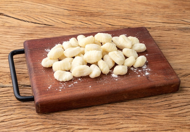 Ongekookte Italiaanse pasta gnocchi op een bord over houten tafel