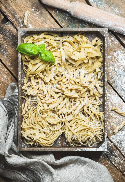 Ongekookte Italiaanse pasta in houten dienblad over armoedige achtergrond