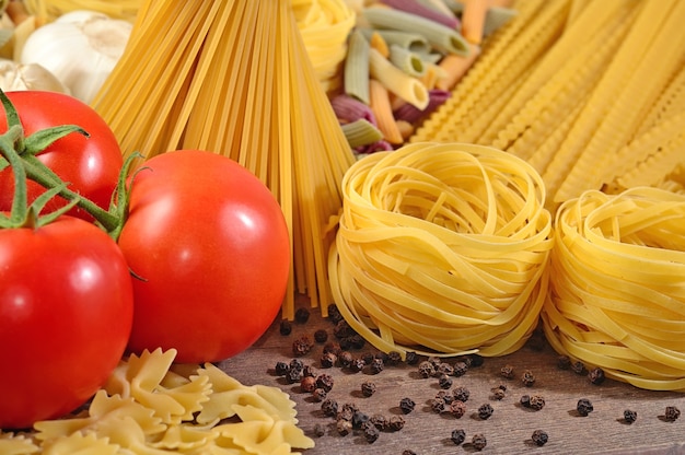 Ongekookte italiaanse pasta, rijpe tomatentak en zwarte peper