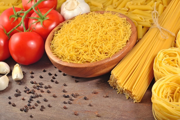 Ongekookte Italiaanse pasta, rijpe tomatentak, knoflook en zwarte p