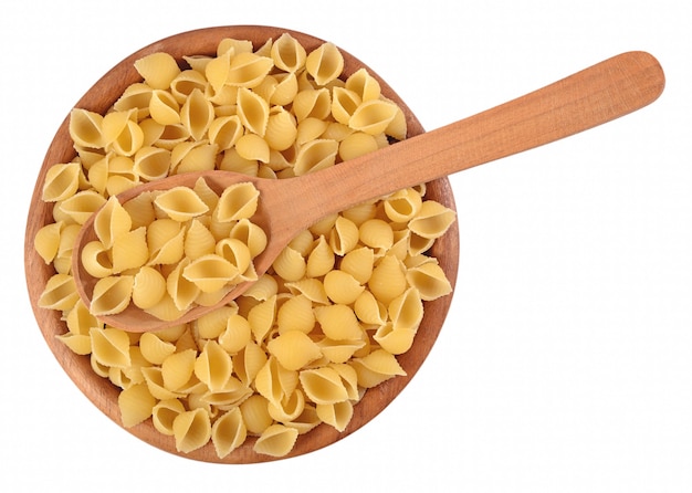 Ongekookte italiaanse pasta schelpen in een houten kom op een witte achtergrond