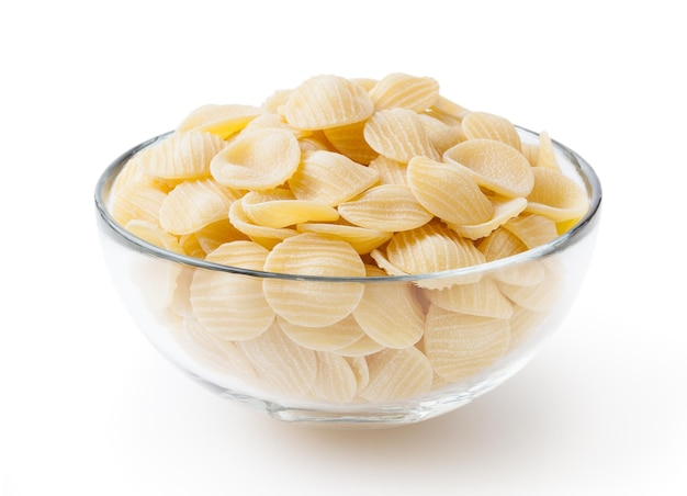 Ongekookte orecchiette pasta in glazen kom geïsoleerd op een witte achtergrond met uitknippad