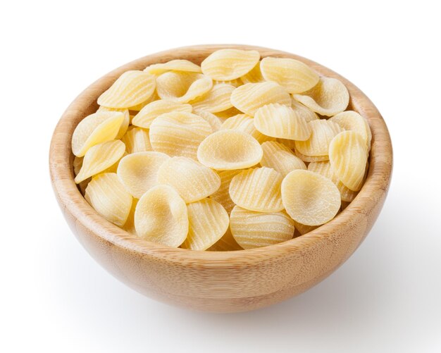 Ongekookte orecchiette pasta in houten kom geïsoleerd op een witte achtergrond met uitknippad