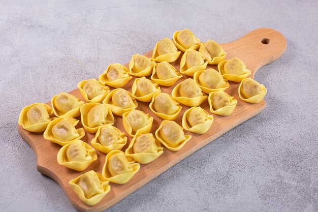 Ongekookte tortelloni met champignonvulling op een houten plank