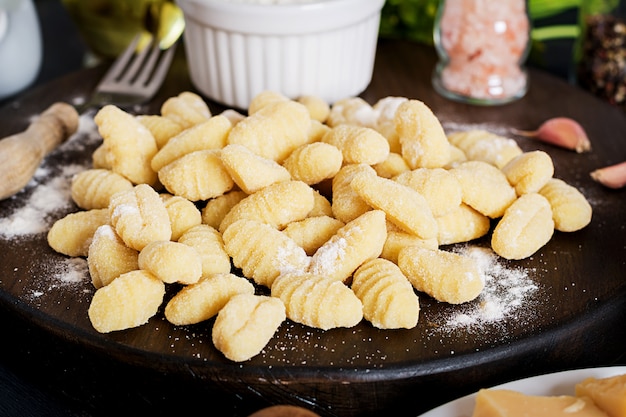 Ongekookte zelfgemaakte gnocchi met een champignonroomsaus en peterselie in kom op een donkere achtergrond.