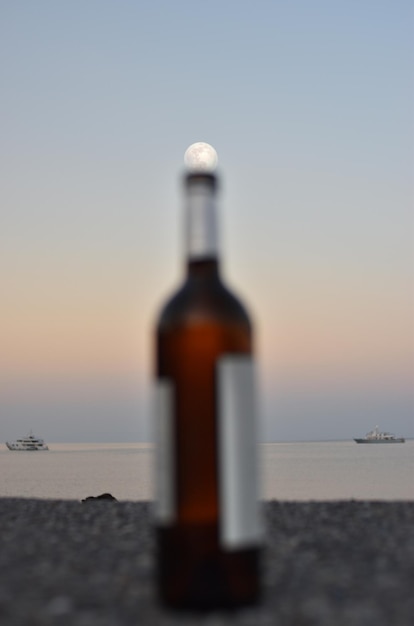 Ongelooflijke volle maan boven de zee en over verlaten flessen op de pier