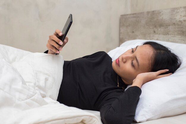 ongelukkig Aziatisch mooi meisje verdrietig met smartphone op bed