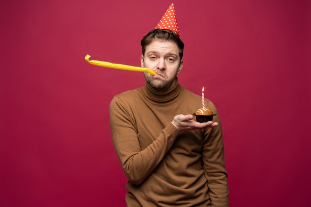 Ongelukkig beklemtoonde jongeman met verjaardag cupcake ongelukkig kijken