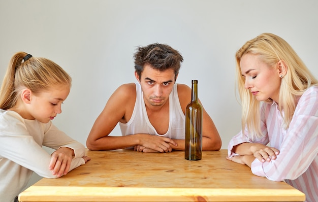 Ongelukkig gezin samen aan tafel zitten, een dronken man brengt alleen problemen voor het gezin