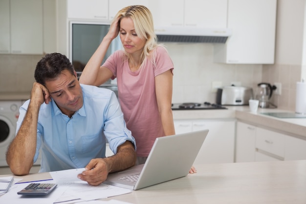 Ongelukkig paar met rekeningen en laptop in keuken