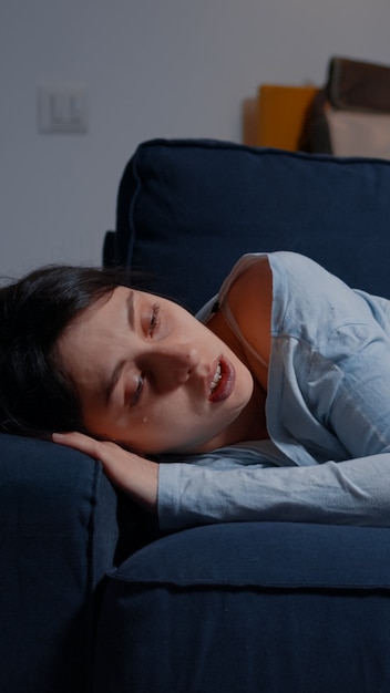 Ongelukkige depressieve vrouw huilend liggend op de bank die lijdt aan slapeloosheid depressie psychologisch probleem...