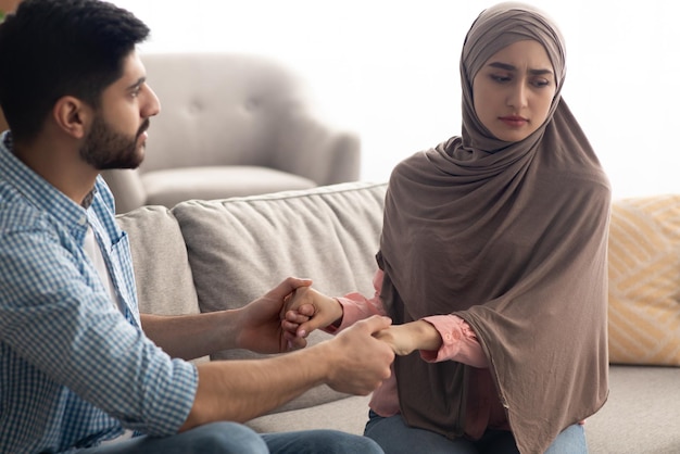 Ongelukkige islamitische echtgenoten hand in hand om thuis te zitten