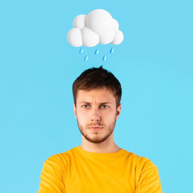 Ongelukkige jonge europese man met abstract wolk en regenteken boven het hoofd geïsoleerd op blauwe studio