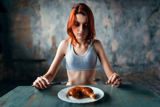 Ongelukkige magere vrouw tegen plaat met eten, gebrek aan eetlust. Vet of calorieën verbranden concept. Gewichtsverlies, anorexia