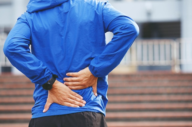 Ongelukkige man die lijdt aan sportblessures tijdens het sporten met lage rugpijn in de wervelkolom met rugpijn mensen gezondheidszorg of medisch en lifestyle concept