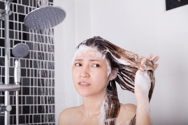 ongelukkige vrouw hoofd wassen met shampoo en douche