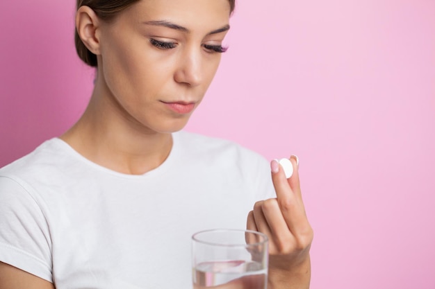 Ongelukkige vrouw houdt pil en glas water vast