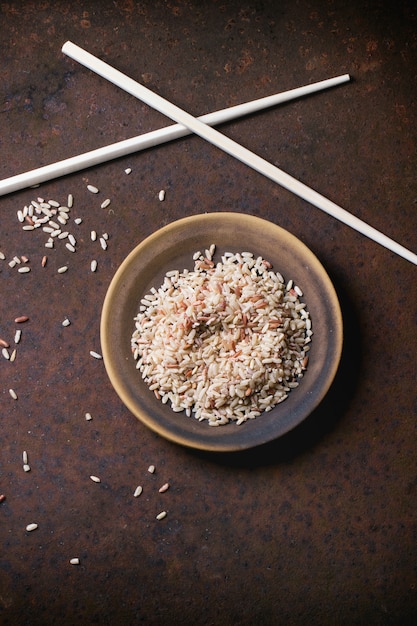 Ongepelde rijst op beton met eetstokjes