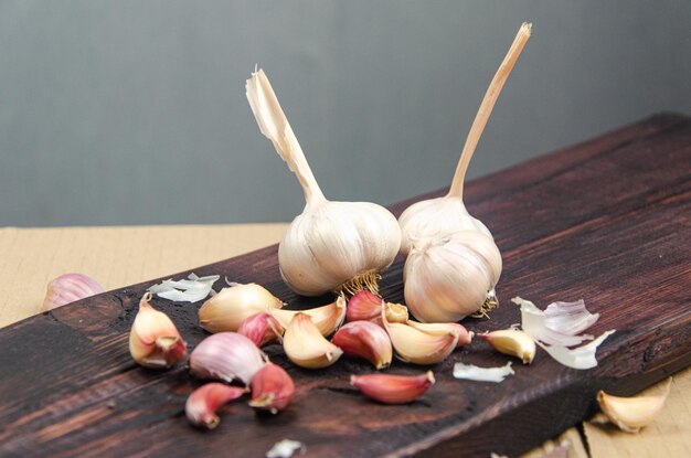 Ongepelde teentjes knoflook tegen de achtergrond van een donkere boom