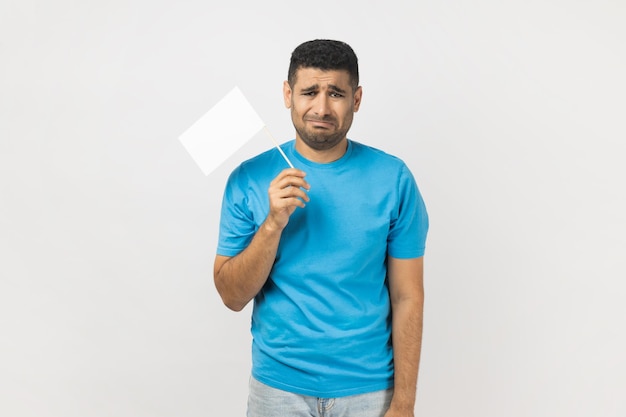 Ongeschoren man die witte vlag vasthoudt en naar de camera kijkt met een huilend gezicht