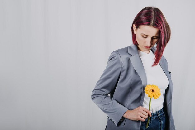 Ongewijzigd openhartig portret van jonge gelukkige jonge vrouw met felrood haar met gele bloem