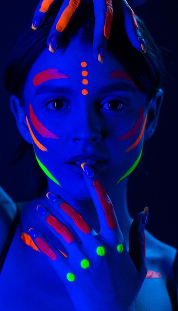 Foto ongewone fluorescerende make-up op de huid van een mooie vrouw die gloeit onder ultraviolet licht