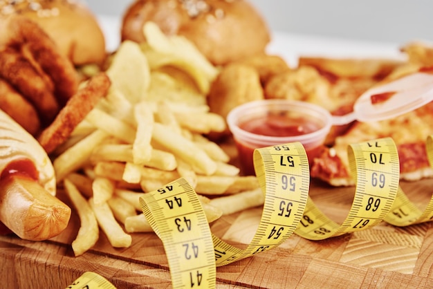 Foto ongezond en junkfood verschillende soorten fastfood en snacks op tafel met meetband