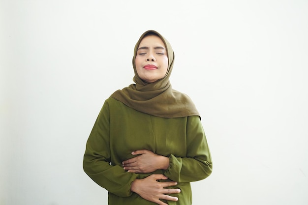 Ongezonde jonge Aziatische moslimvrouw die staat met het aanraken van zijn buik met maagpijn