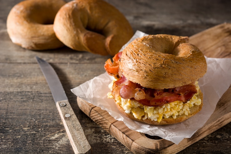 Foto ongezuurd broodjesandwich met bacon, ei en kaas op houten lijst.