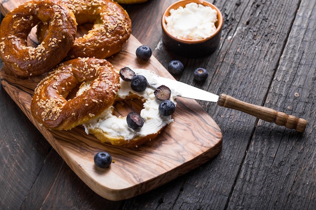 Ongezuurde broodjessandwich met roomkaas en op bosbes op houten lijst