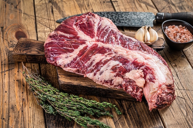 Onglet or hanger raw beef meat steak on butcher board with knife. wooden table. Top View.