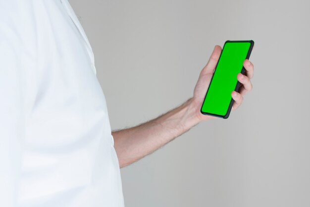 Onherkenbaar arts met een smartphone met groen scherm in het ziekenhuis.