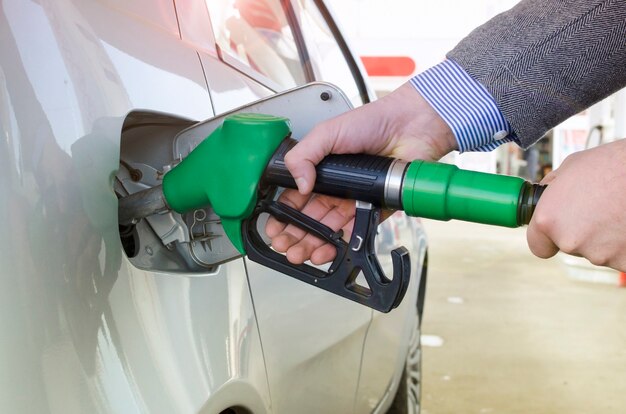 Onherkenbaar persoon die auto bij tankstation tanken.