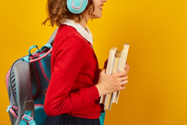 Onherkenbaar Schoolmeisje met rugzakkoptelefoon en boeken ter beschikking terug naar school